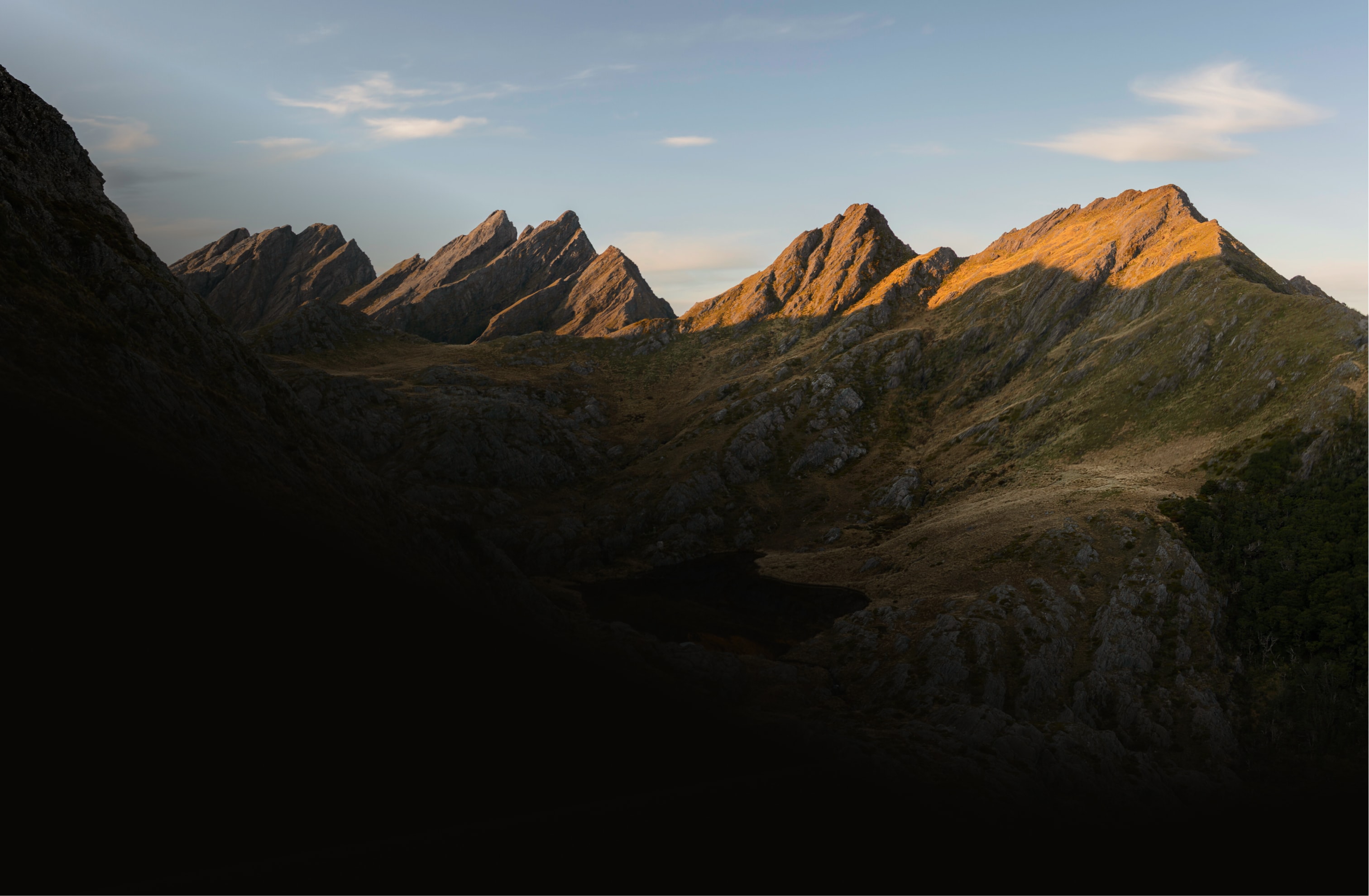 Golden mountain ranges at dusk under a soft sky